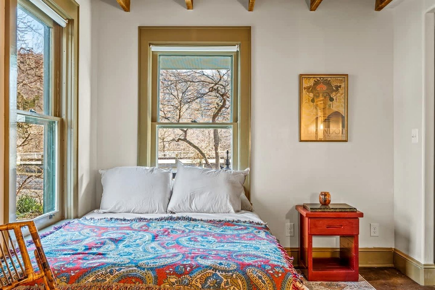 Un dormitorio con una cama grande, una ventana con vistas, una mesita pequeña y una silla.
