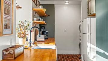 A compact kitchen with a wooden countertop, a sink, a stove, and a refrigerator.
