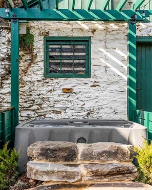 A stone wall with a window and a stone bench.