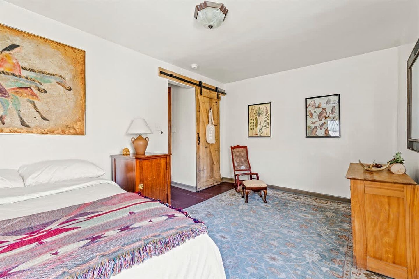 Een slaapkamer met een bed, een stoel, een bureau en een deur.