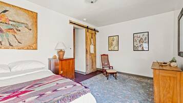 Een slaapkamer met een bed, een stoel, een bureau en een deur.