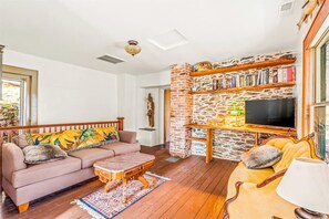 A living room with a sofa, armchair, coffee table, and a fireplace with a TV.