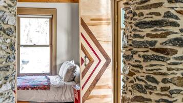 A room with a bed, a window, and a stone wall.