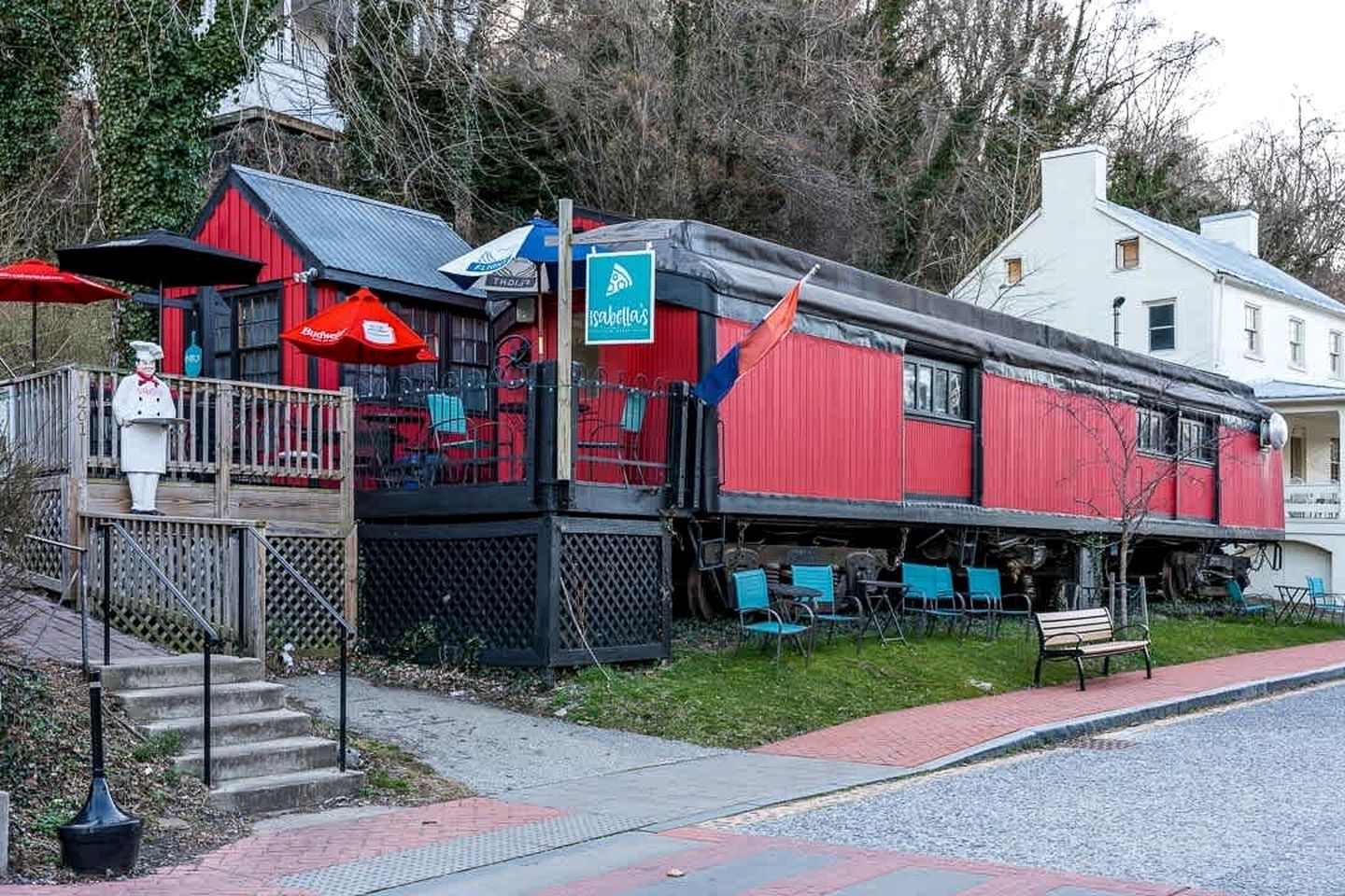 A red building with outdoor seating, a flag, and a statue.