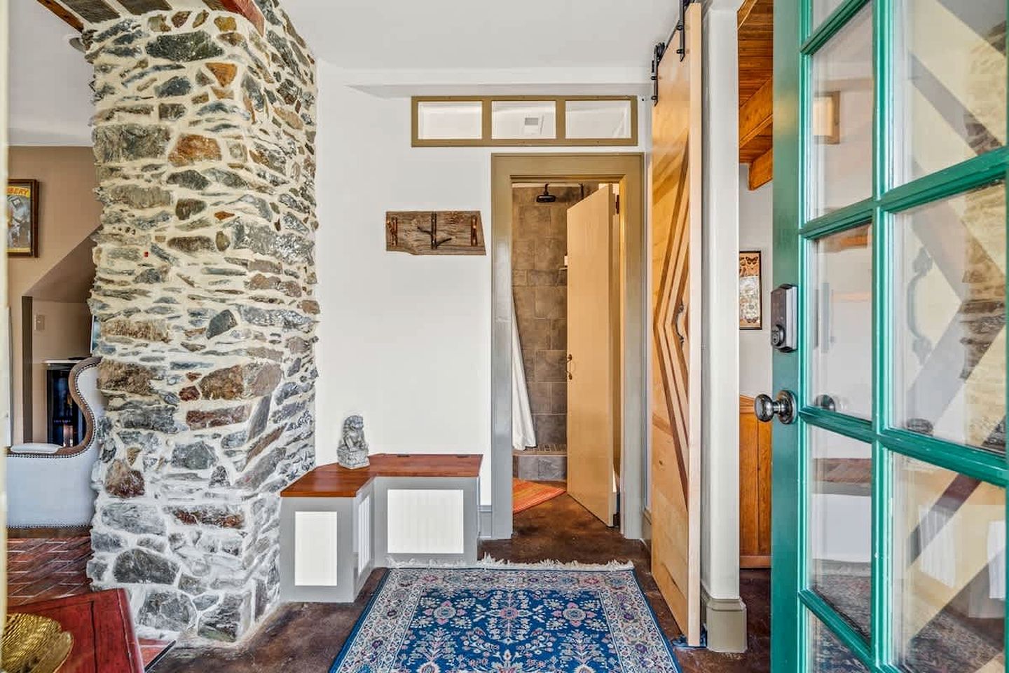 Un pilier de pierre, une porte en bois et un tapis bleu à motifs dans un couloir.