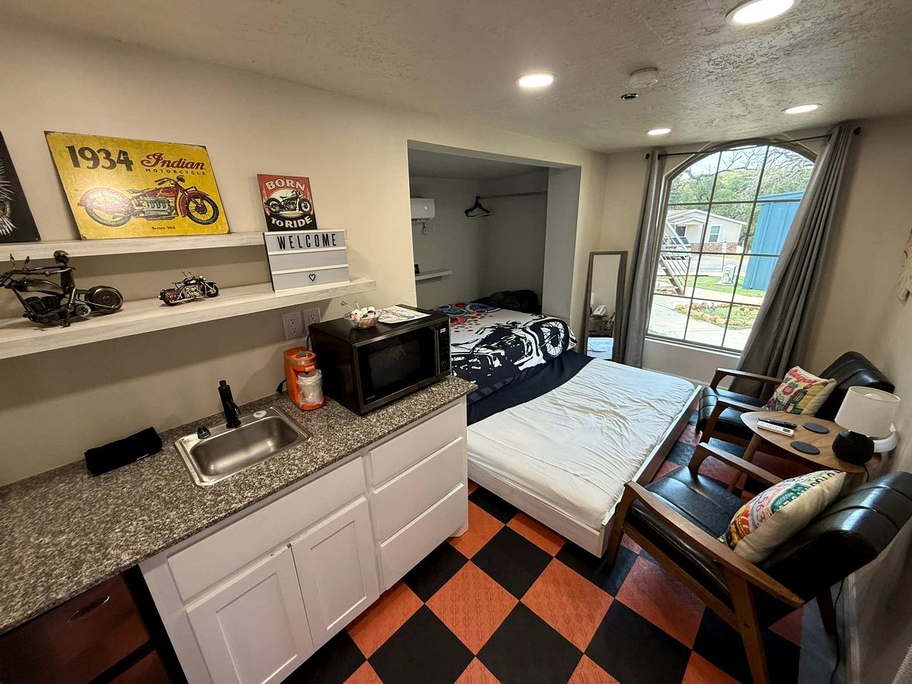 Habitación de hotel compacta con kitchenette, cama, una pequeña zona de estar y ventana con vistas.