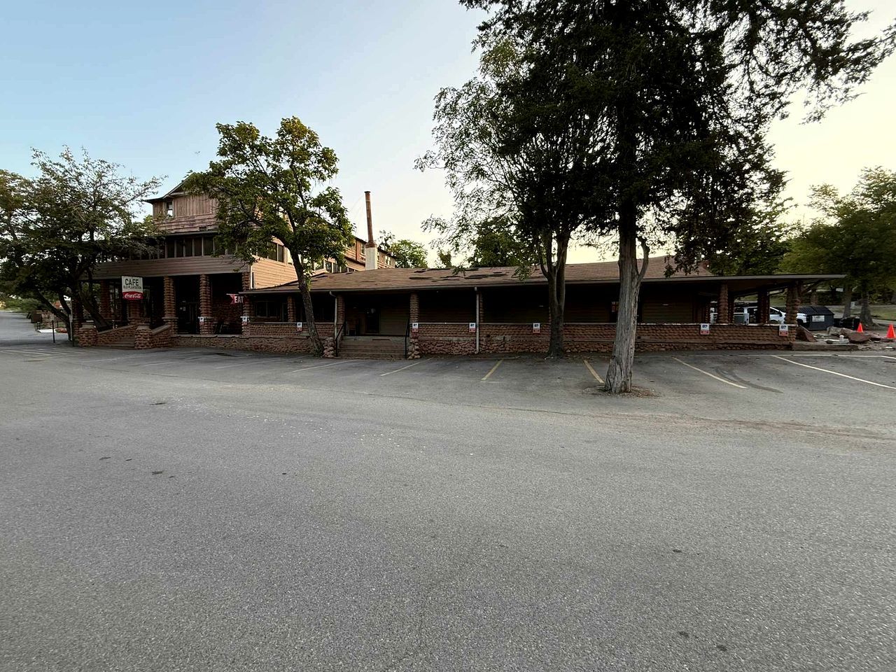 A building with a brick facade, a covered parking area, and a sign indicating a cafe.