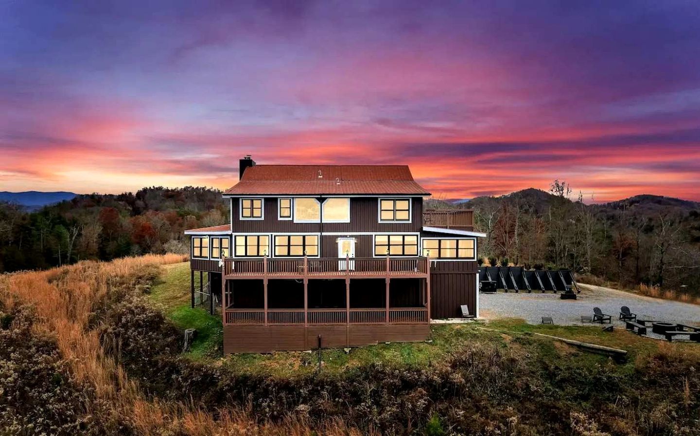 A two-story house with a large balcony, surrounded by a natural landscape.