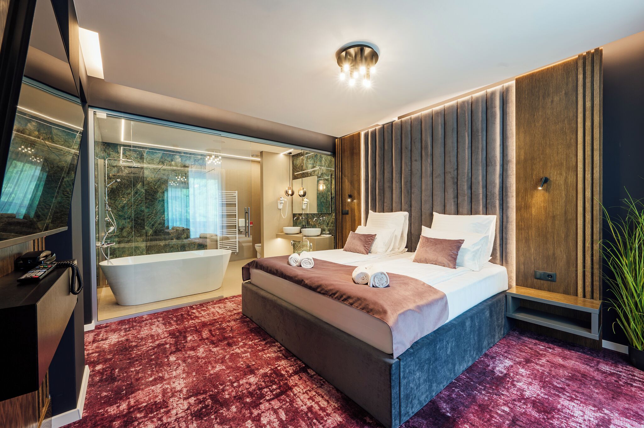 A modern hotel room with a large bed, a separate bathroom, and a glass-enclosed shower area.