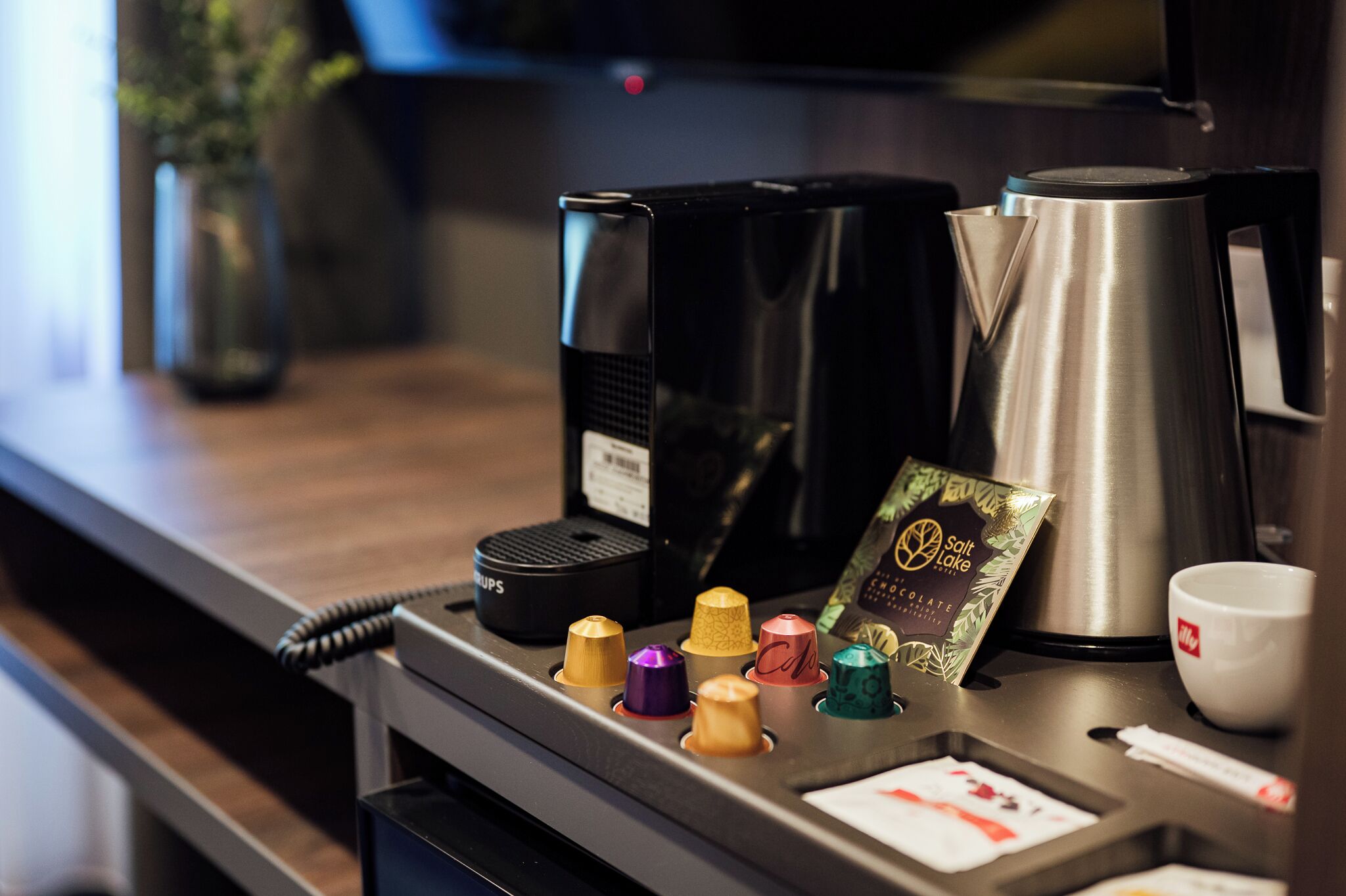 A coffee machine, a salt and pepper shaker, a packet of coffee creamer, and a white cup on a counter.