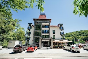 A hotel with a prominent sign, multiple floors, and a parking area with several cars.