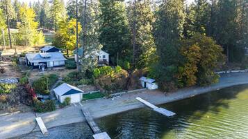 A lakeside property with a dock, a small shed, and a house with a metal roof.