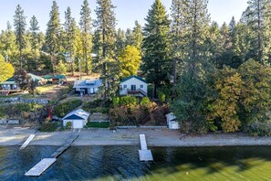 A residential area with houses surrounded by dense forest, a dock, and a small boat.
