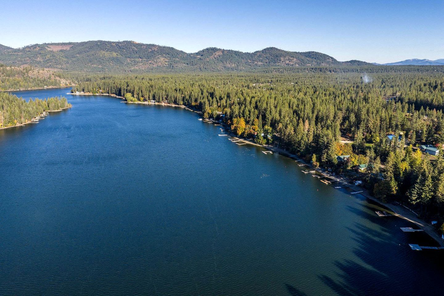 Ein See, umgeben von dichtem Wald und Bergen.