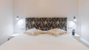 Een bed met een hoofdbord met patroon, nachtkastjes en wandlampen.