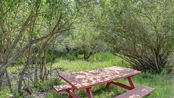 Una mesa de picnic en un entorno natural, rodeada de follaje denso.