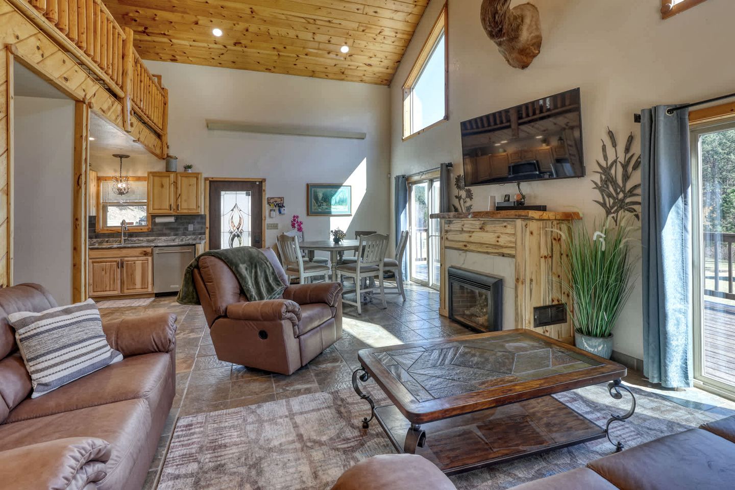 A spacious living area with a fireplace, leather furniture, and a high ceiling.