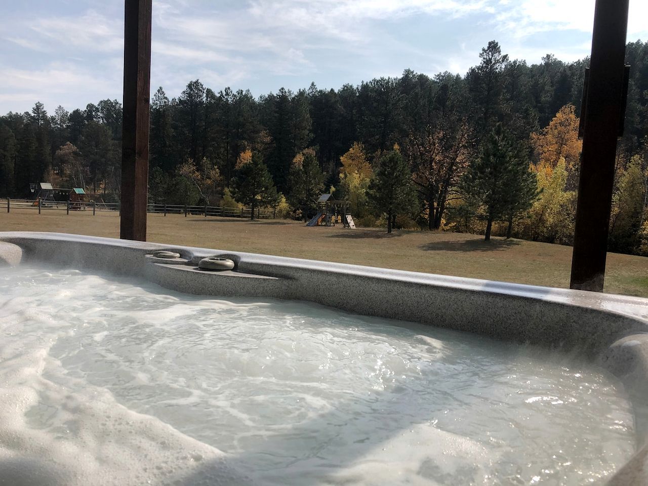 Un jacuzzi con vistas a un área boscosa y un parque infantil.