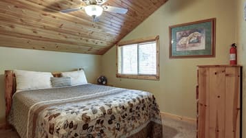A bedroom with a bed, a ceiling fan, a window, and a painting on the wall.