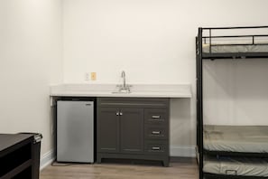 Ein kleines Zimmer mit Küchenzeile, inklusive Kühlschrank, Spüle und Schränken.