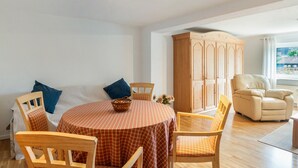 Un comedor con una mesa redonda, sillas, un armario y una ventana con vistas.
