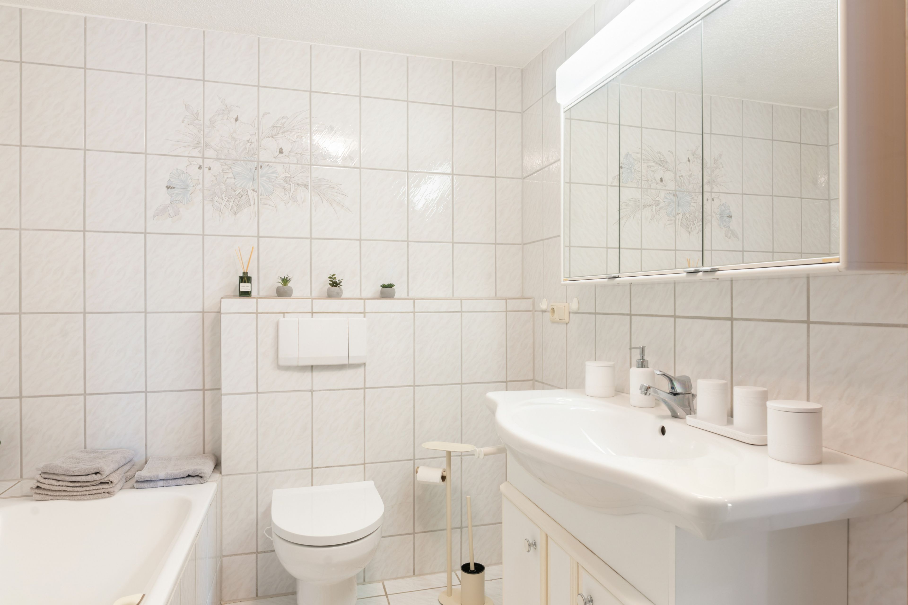 Ein Badezimmer mit Badewanne, Toilette und Waschbecken mit Spiegel darüber.