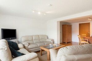 Una sala de estar con sofá, mesa de centro y televisión.