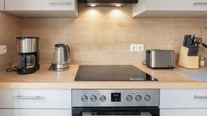 Una cocina moderna con horno integrado, cafetera, tostadora y bloque de cuchillos.