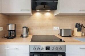 A modern kitchen with a built-in oven, a coffee maker, a toaster, and a knife block.