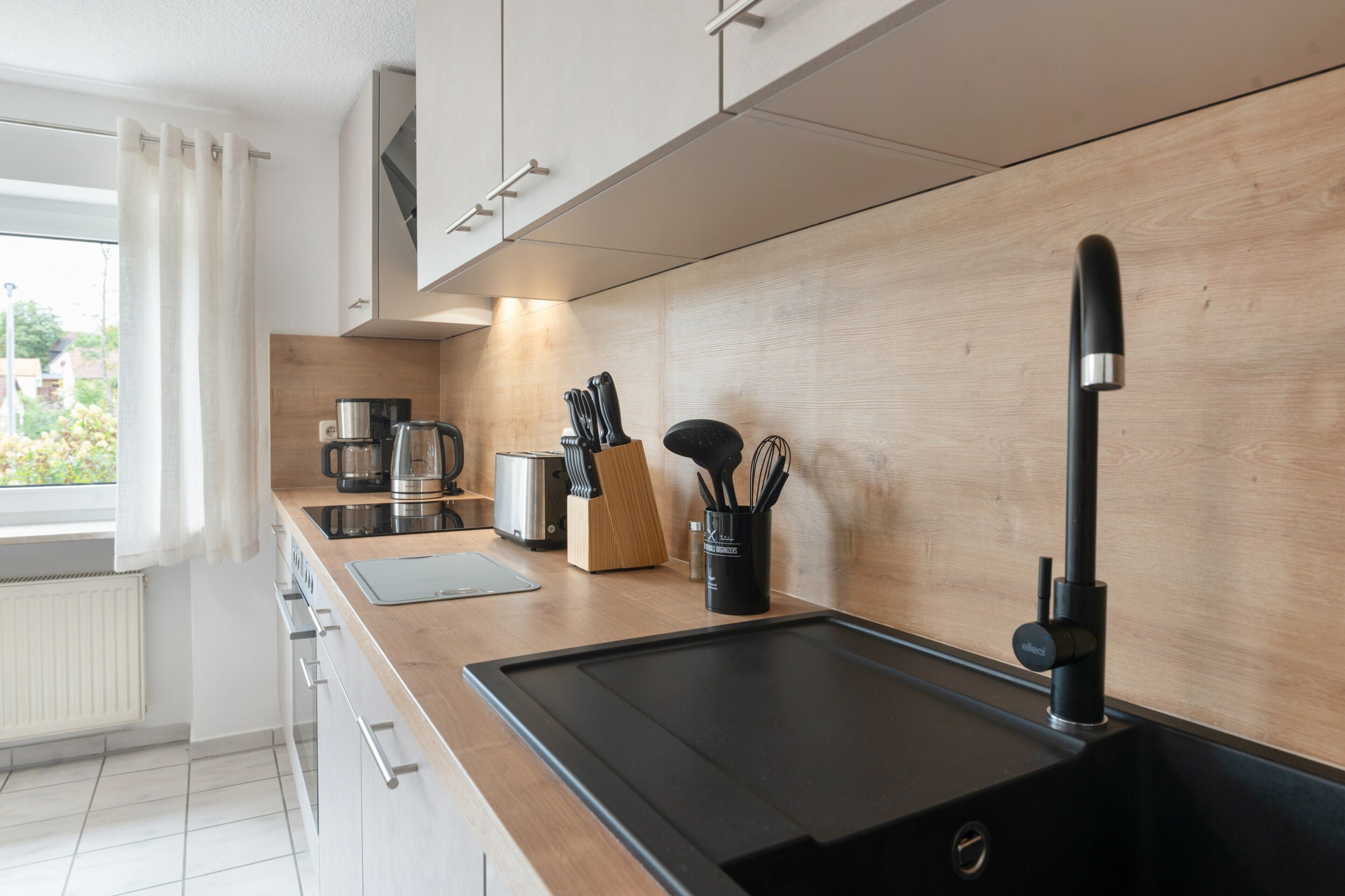 Eine moderne Küche mit einer Holzarbeitsplatte, einem schwarzen Wasserhahn und einem Toaster.