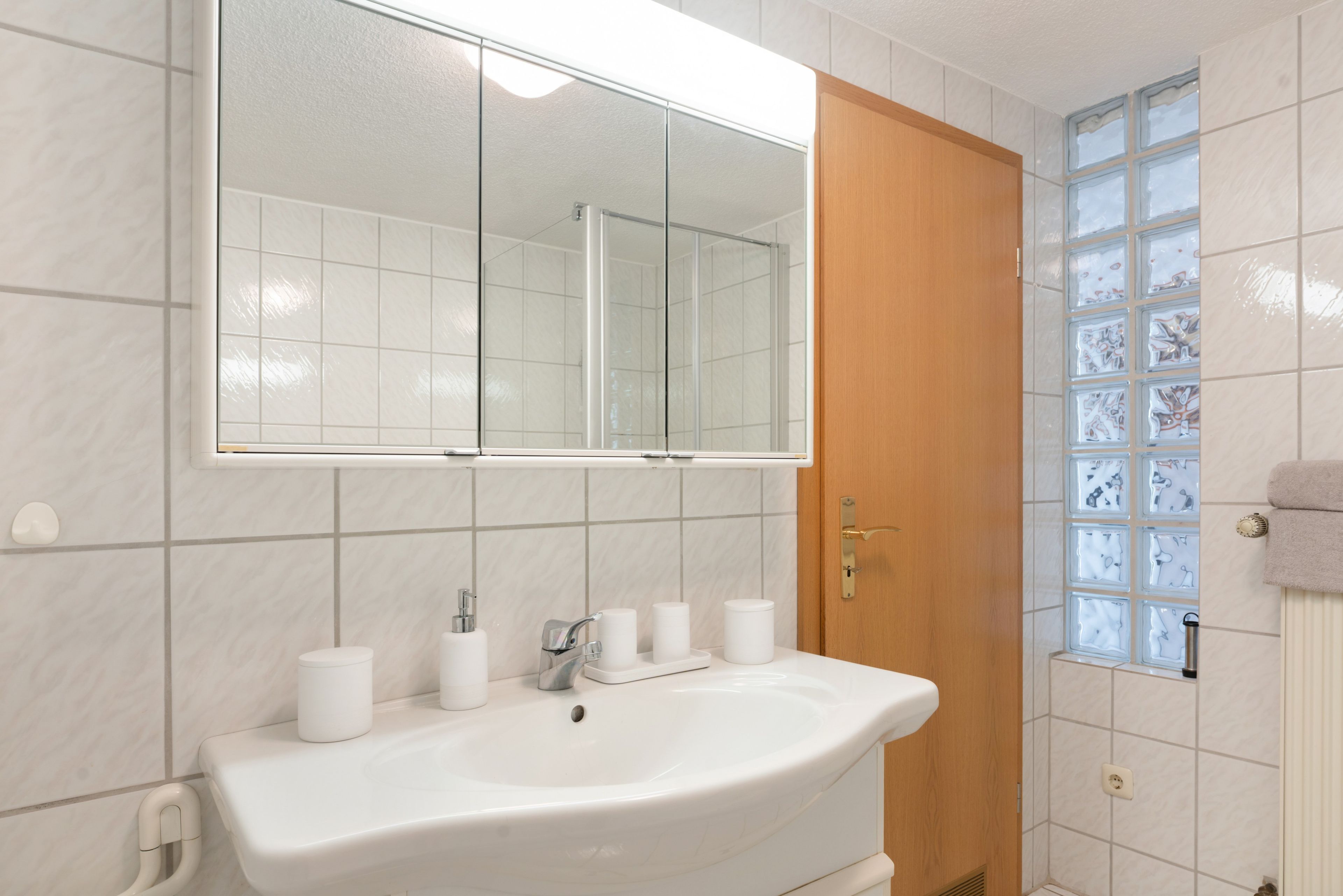 Une salle de bain avec un lavabo, un miroir et des toilettes, le tout de couleur blanche.