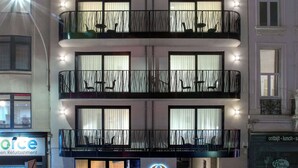 Un hôtel à plusieurs étages, doté de balcons, de grandes fenêtres et d’un logo « Q » bien visible.