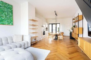 Uma sala de estar moderna com sofá, área de jantar com mesa e cadeiras e estantes embutidas de madeira.