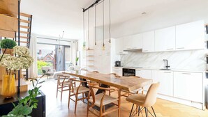 A modern kitchen with white cabinets, a wooden dining table, and a herringbone floor pattern. - Bright Duplex with Balcony in Antwerp (Antwerpen)