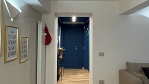 A hallway with a wooden floor, a blue door at the end, and a beige sofa on the right. - La Casa di Joy (Naples)