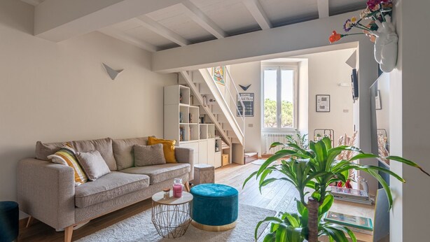 A living room with a sofa, a coffee table, a blue ottoman, and a potted plant. - La Casa di Joy (Naples)
