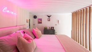 A bedroom with a bed, a neon sign, a clock, and a dresser. - La Casa di Joy (Naples)