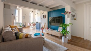 A modern living room with a sofa, a coffee table, and a TV. There is a staircase leading to another level. - La Casa di Joy (Naples)