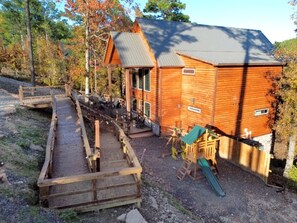 Eine Holzhütte mit einer Terrasse und einem Spielbereich.
