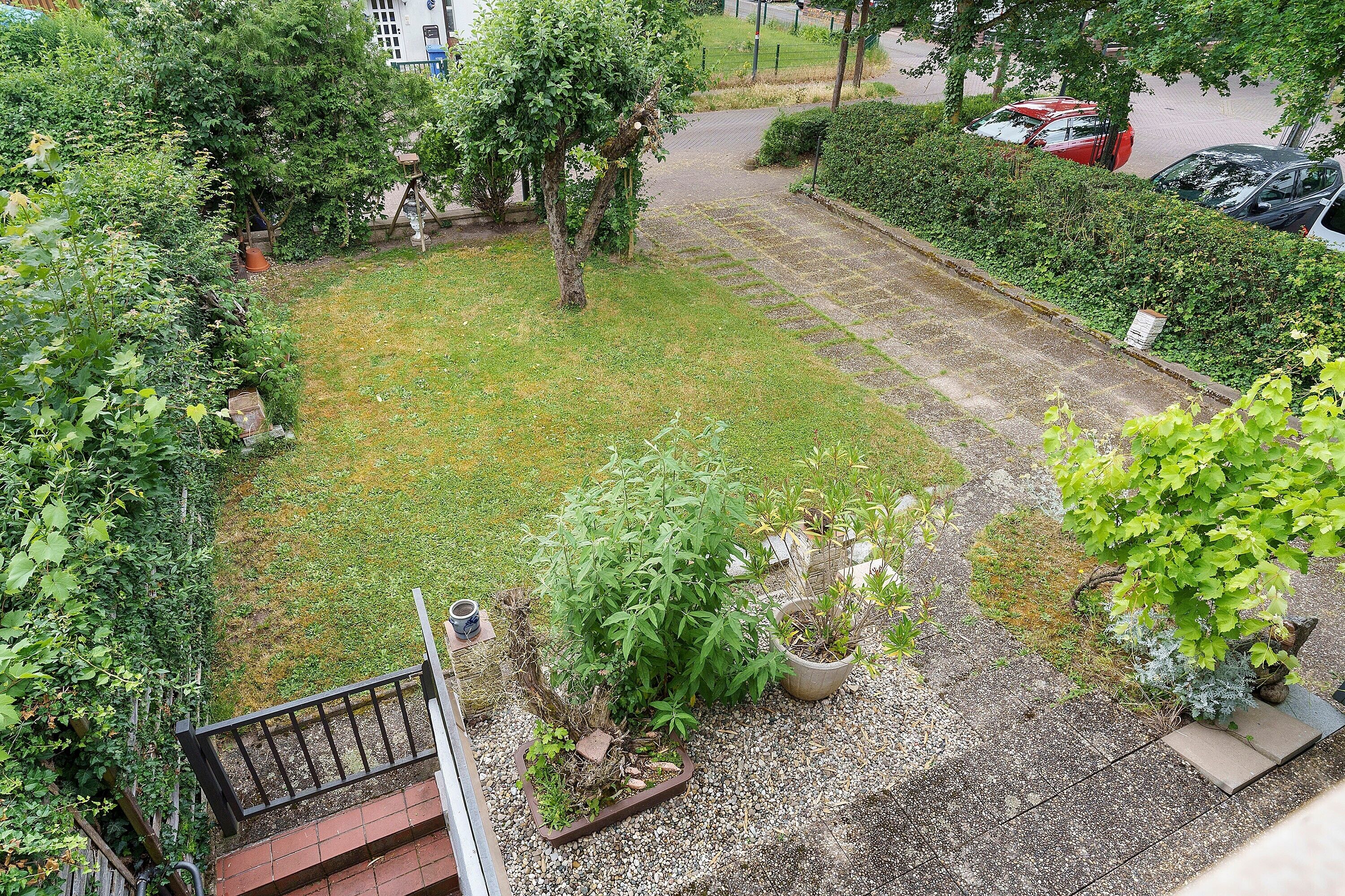 Ein Garten mit Sitzplatz, Kübelpflanzen und einer Treppe.