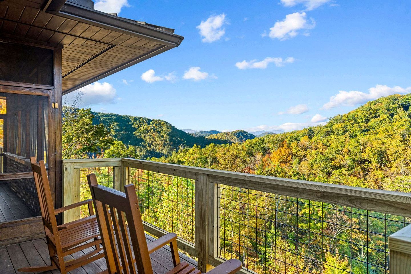 A wooden deck with a view of a forested mountain range.