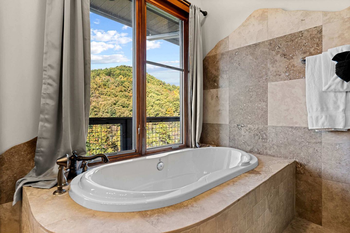 A bathroom with a freestanding bathtub, a window with curtains, and a towel rack.