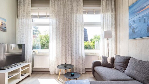 En moderne stue med sofa, fjernsyn og et lille bord.