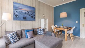 En moderne stue med en grå sofa, et spisebord med stole, et stort billede og en blå væg.