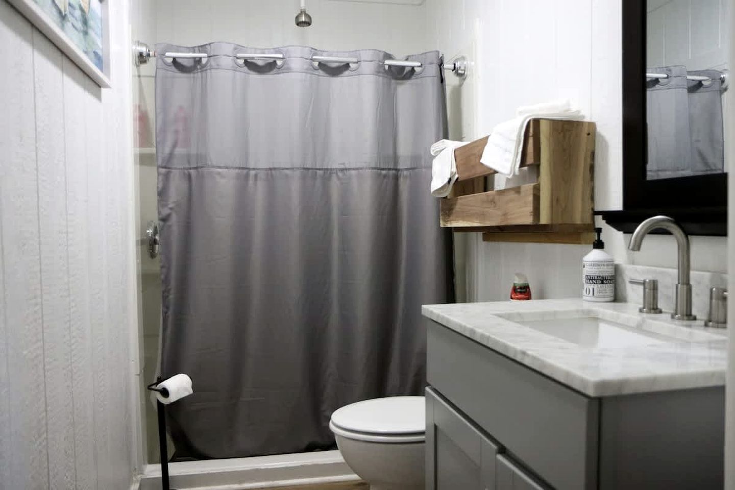 A bathroom with a shower curtain, toilet, sink, and a mirror.