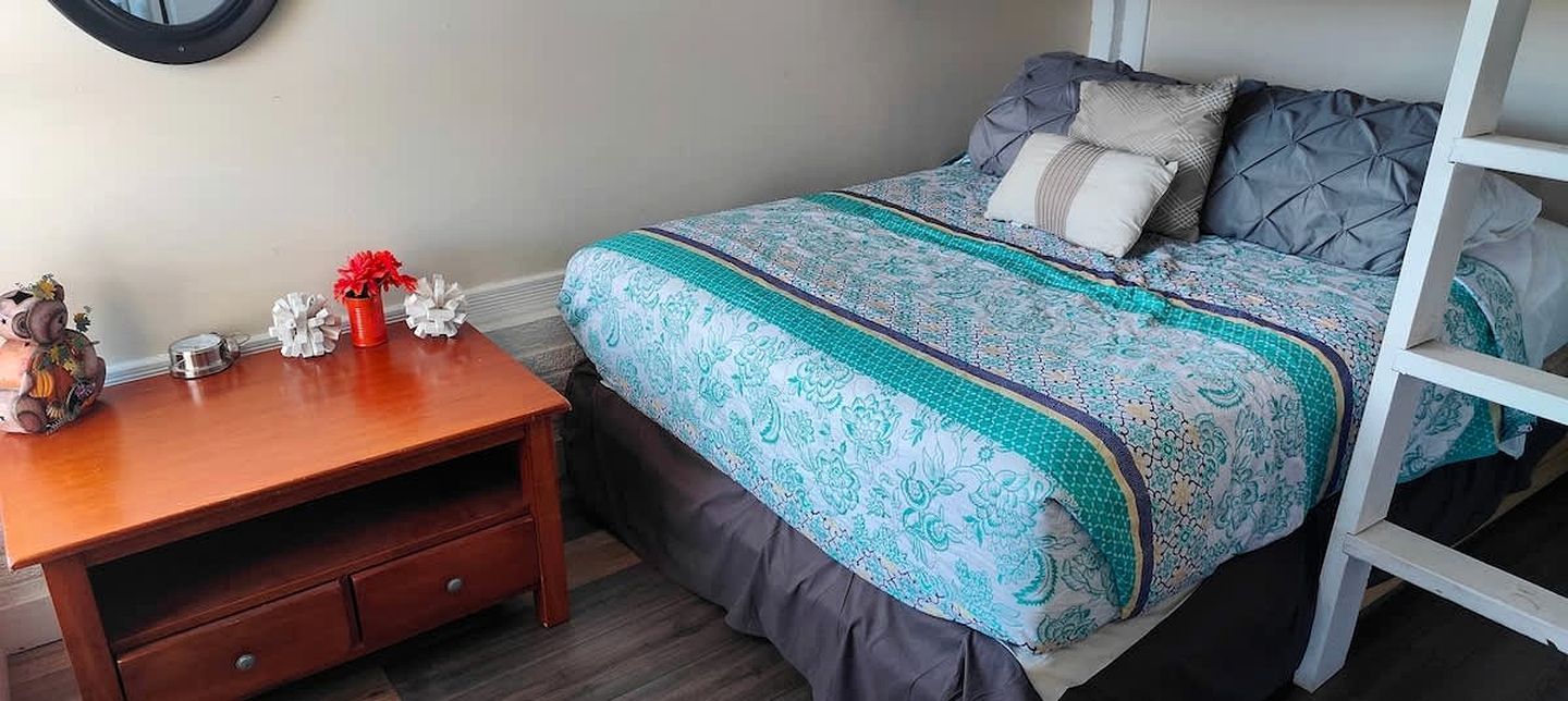A bedroom with a bunk bed, a wooden nightstand, a decorative pig figurine, and a vase with red flowers.