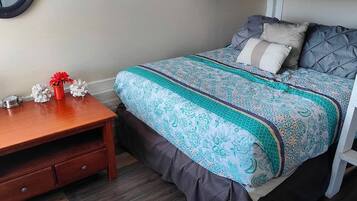 A bedroom with a bunk bed, a wooden nightstand, a decorative pig figurine, and a vase with red flowers.
