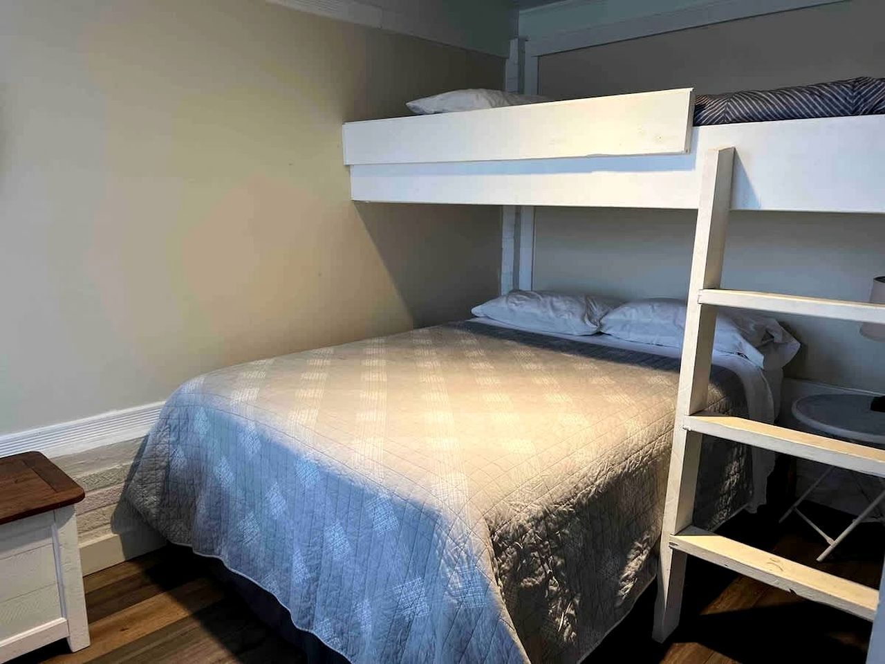 Una cama litera con una cama inferior, una mesita de noche y una silla.