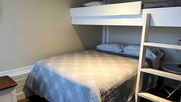 Una cama litera con una cama inferior, una mesita de noche y una silla.