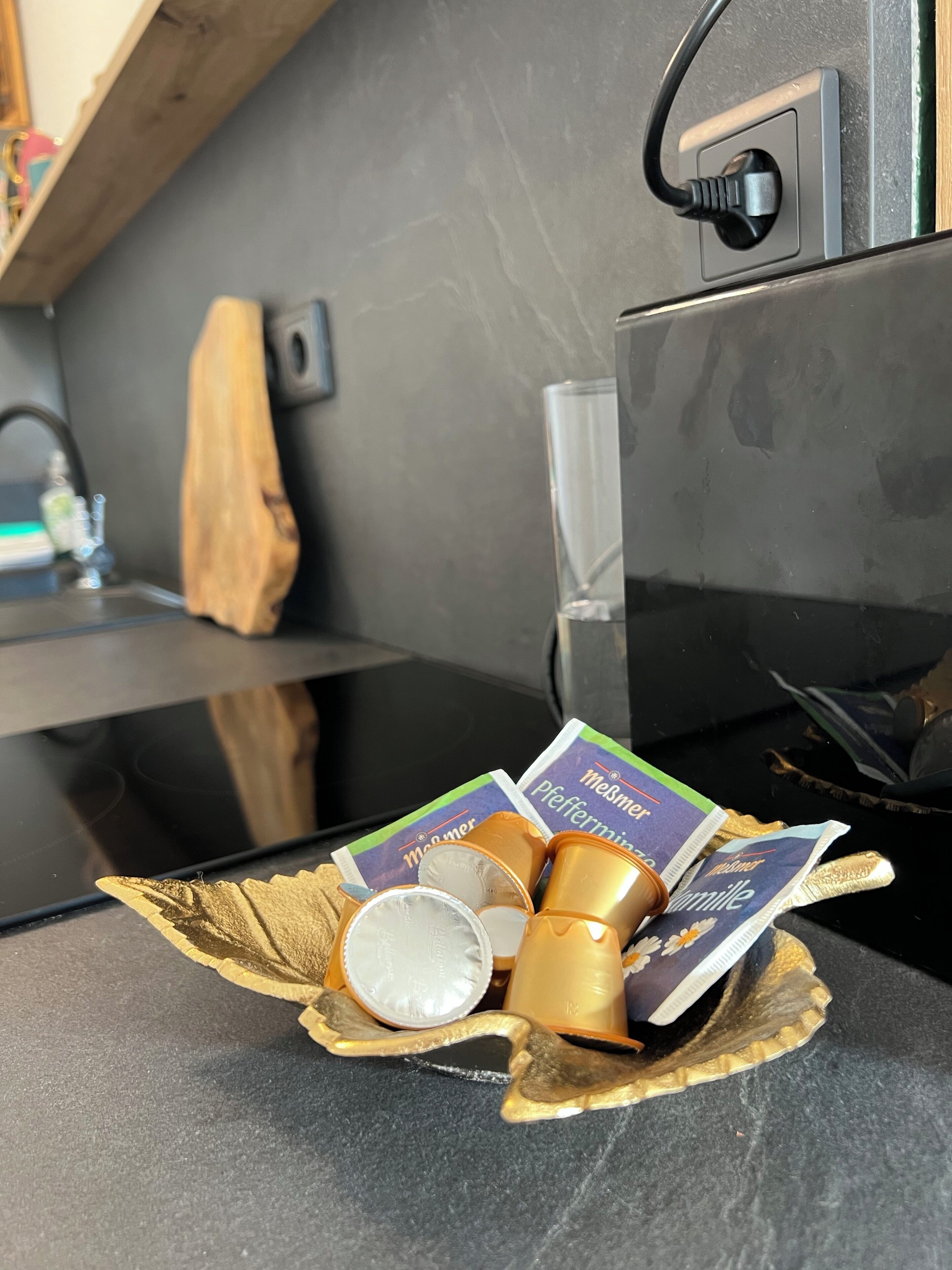 A kitchen counter with a microwave, a glass, and packaged food items.